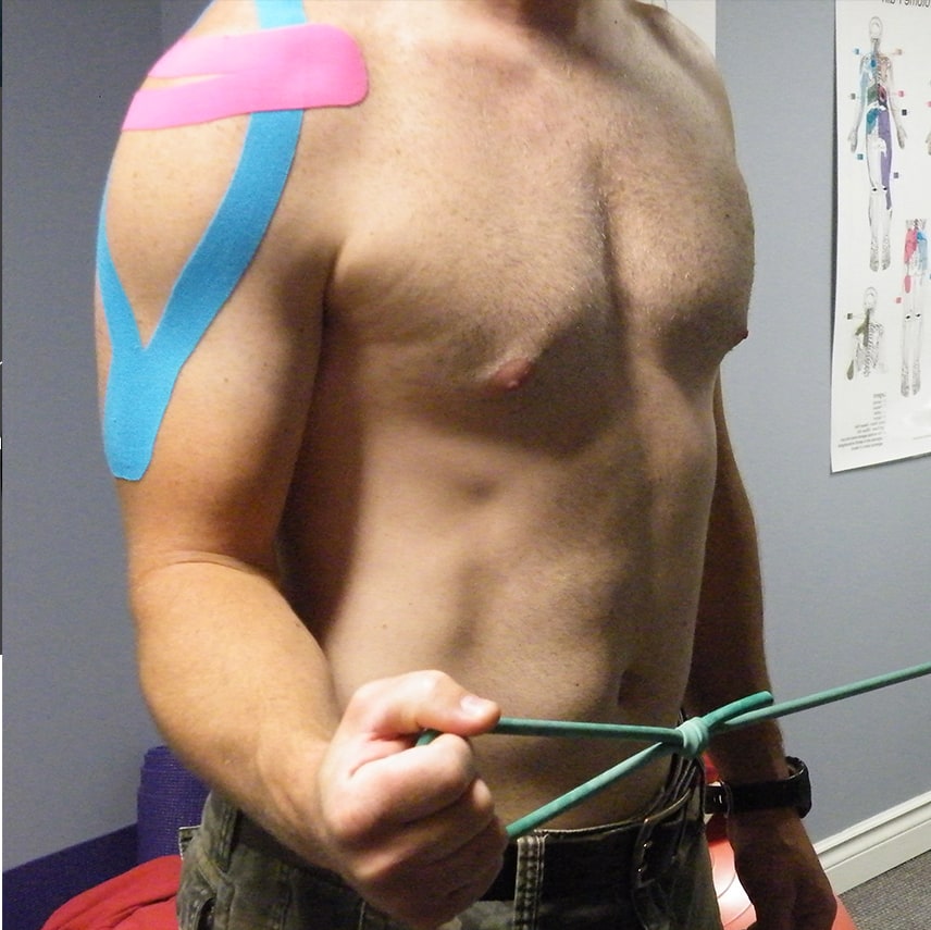 Exercice de réadaptation de l’épaule avec bandes élastiques et taping thérapeutique