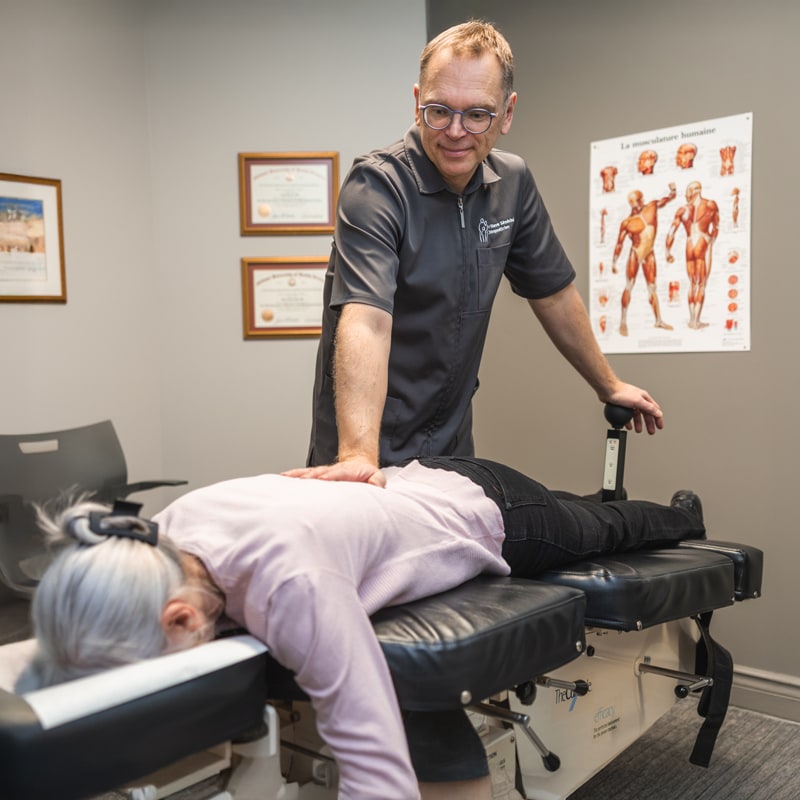 Chiropraticien effectuant un traitement sur table de flexion-distraction avec la technique Cox